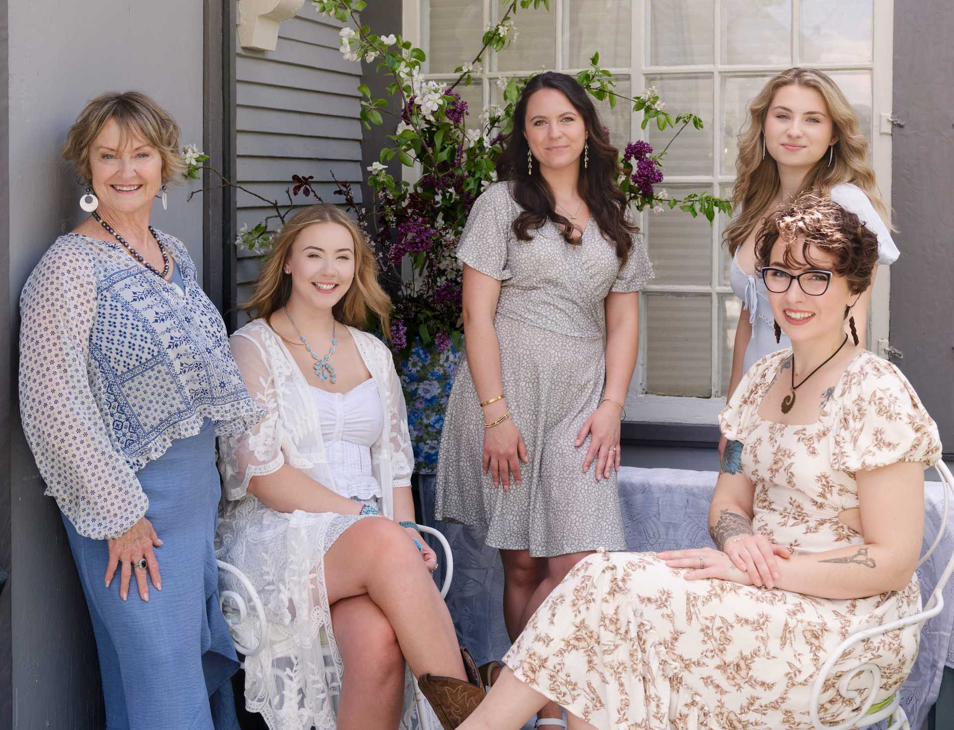 Group of five women posing outside, dressed in casual spring outfits.